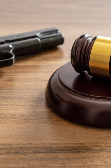 Gavel and handgun on wooden surface, symbolizing New Jersey Red Flag Law and legal issues surrounding gun control.